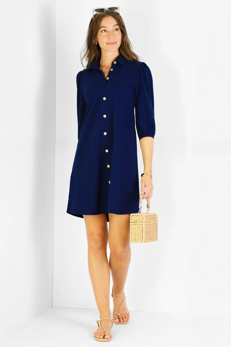 Woman wearing a navy blue dress holding a woven bag on a white background