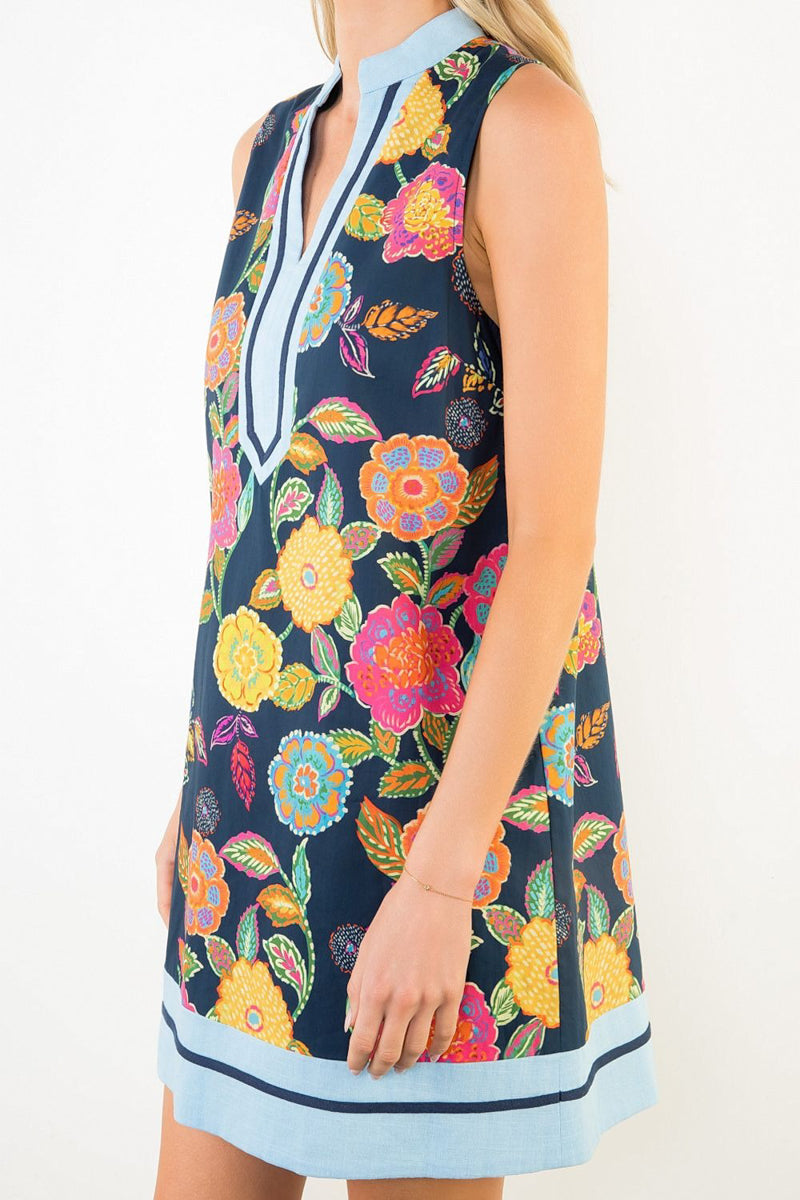 Woman wearing a colorful floral dress with a blue trim on a white background