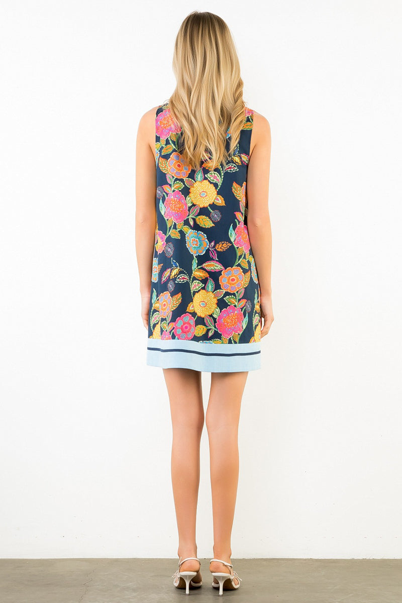 Woman wearing a sleeveless floral dress with a white background