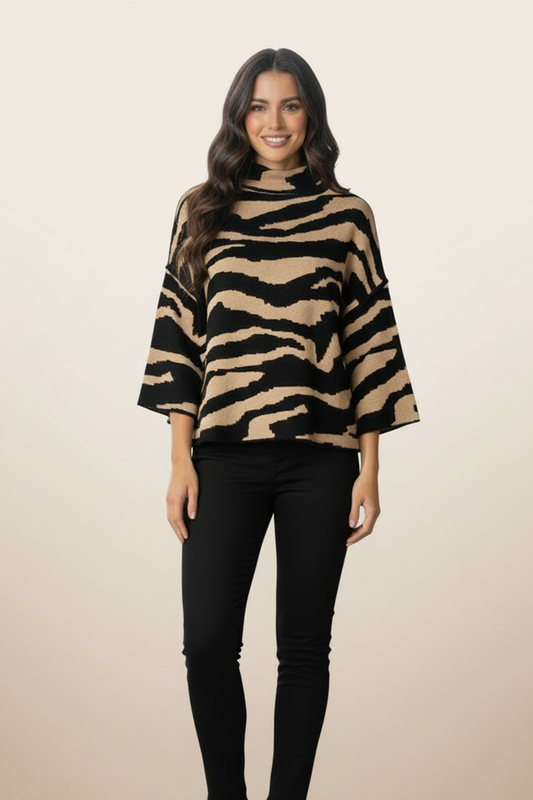 Woman wearing a black and beige zebra print poncho against a beige background