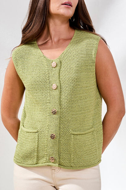 Woman wearing a green knitted vest with buttons on a white background
