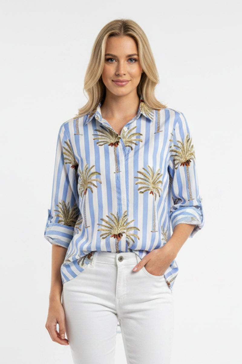 Woman wearing a blue and white striped shirt with palm tree patterns on a white background