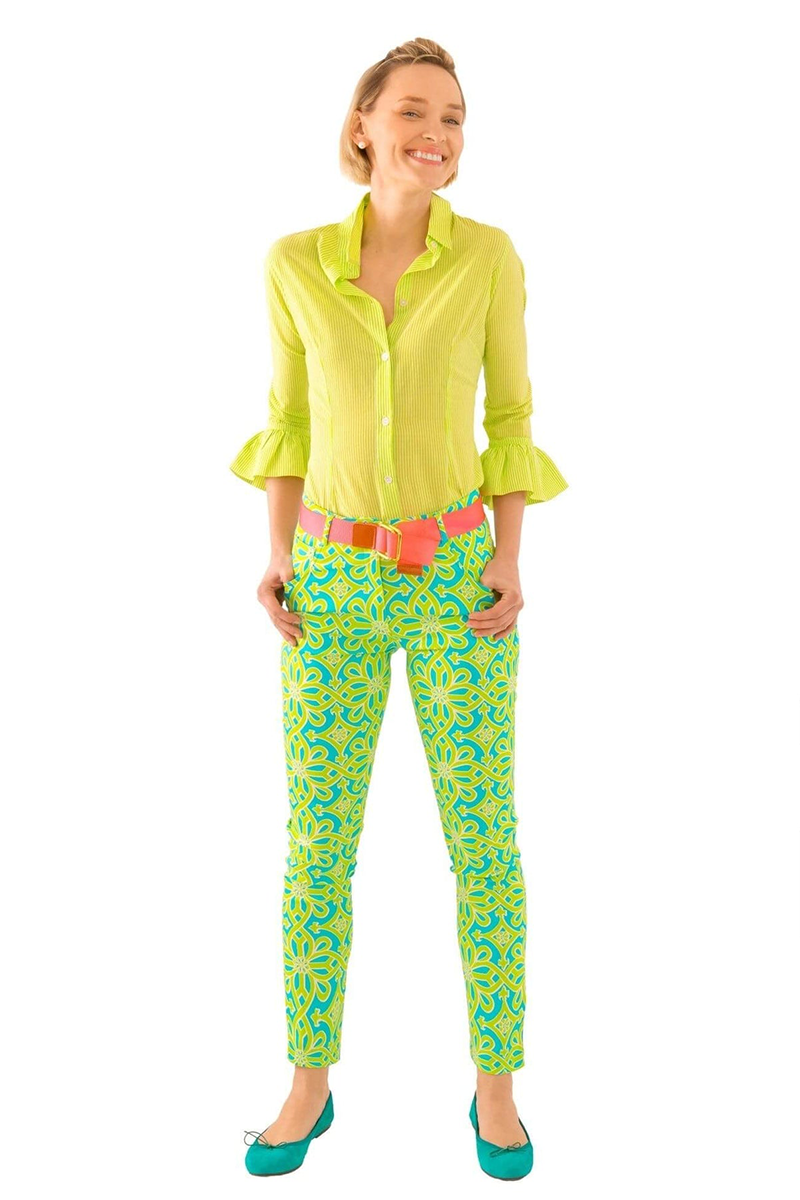 Woman wearing a bright green outfit with a pink belt on a white background