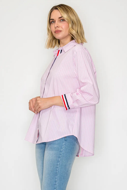 Woman wearing a light pink striped shirt with a collar and blue jeans on a white background