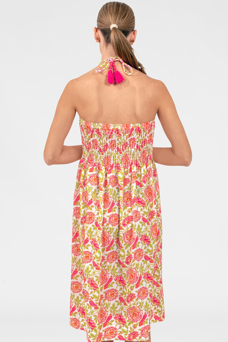 Woman wearing a floral dress with pink tassel accents on a white background