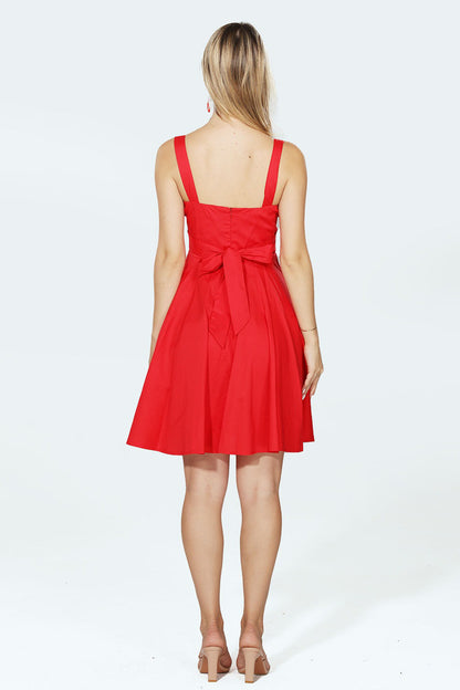Woman wearing a red dress with a bow detail on a white background