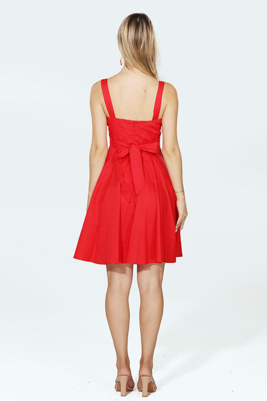 Woman wearing a red dress with a bow detail on a white background
