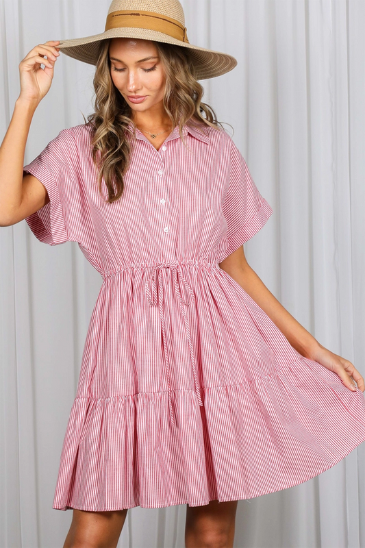 Woman wearing a red stripe dress with a wide-brimmed hat against a neutral background