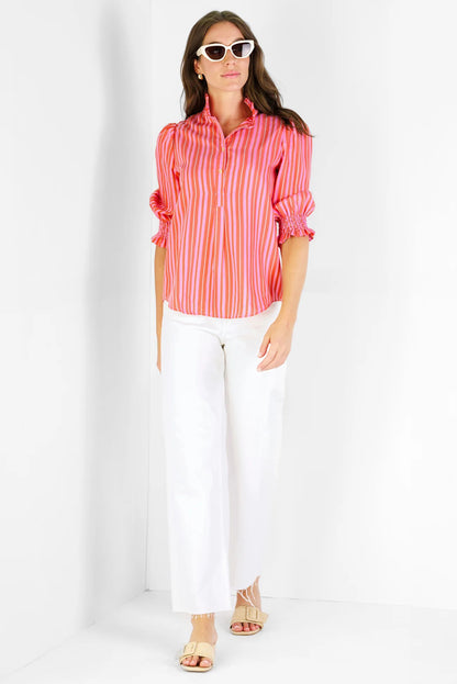 Woman wearing a red and pink striped shirt and white pants on a white background
