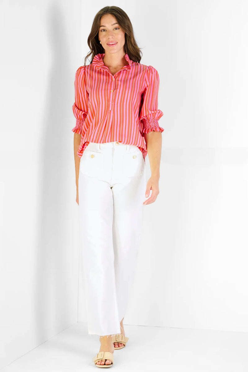 Woman wearing a red and pink striped shirt and white pants on a white background