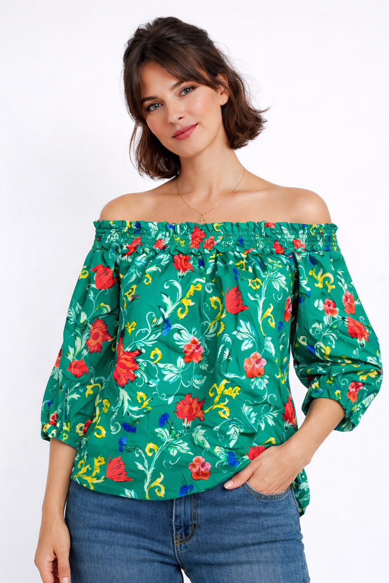 Woman wearing a green floral off-shoulder top against a white background