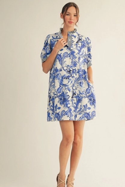 Woman wearing a blue and white floral dress on a plain background