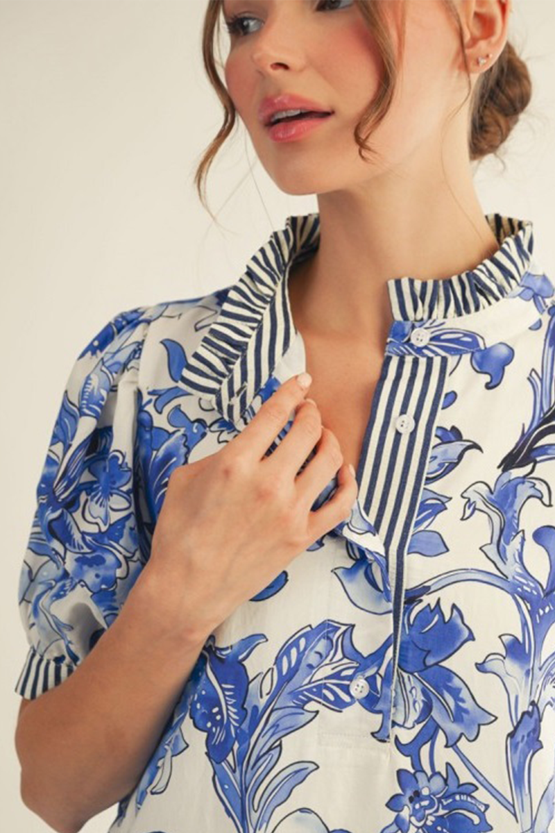 Woman wearing a blue and white floral patterned blouse against a plain background