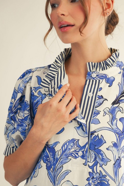 Woman wearing a blue and white floral patterned blouse against a plain background