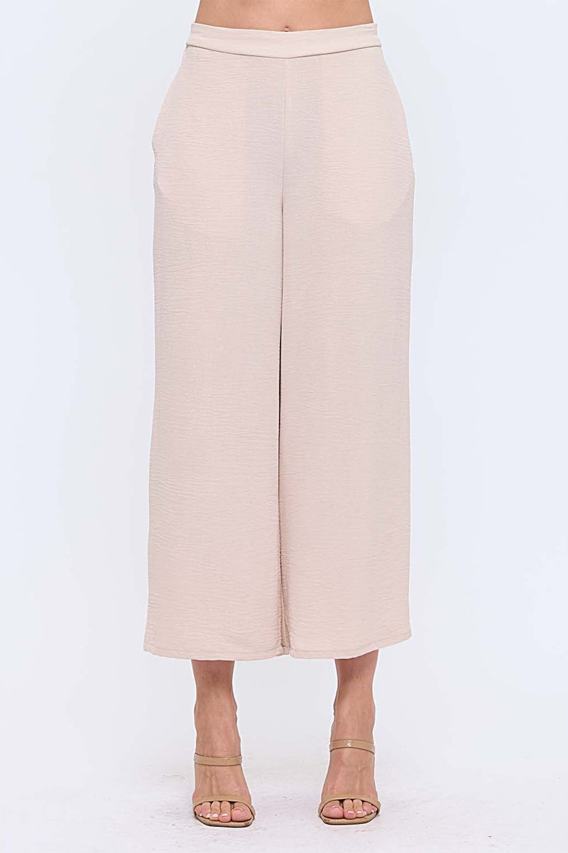 Woman wearing neutral wide leg pants with nude heels on white background