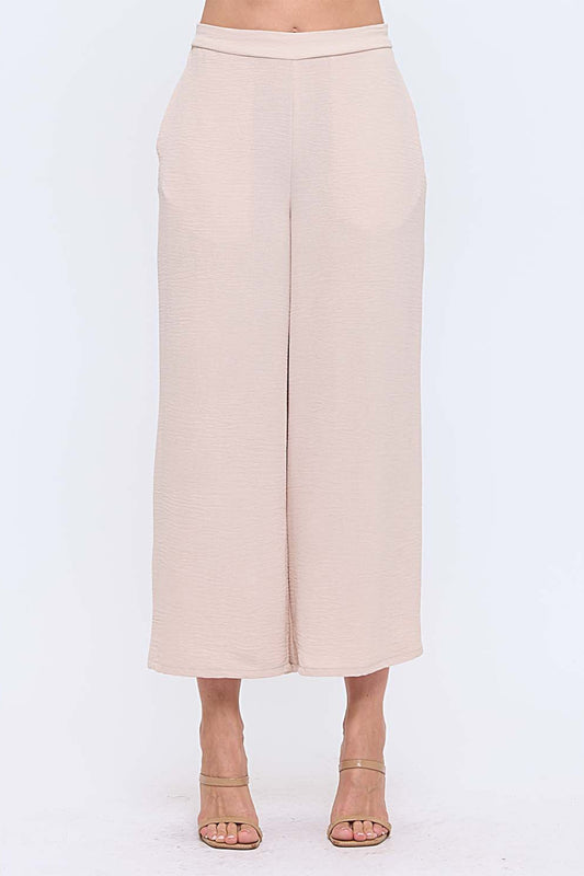 Woman wearing neutral wide leg pants with nude heels on white background
