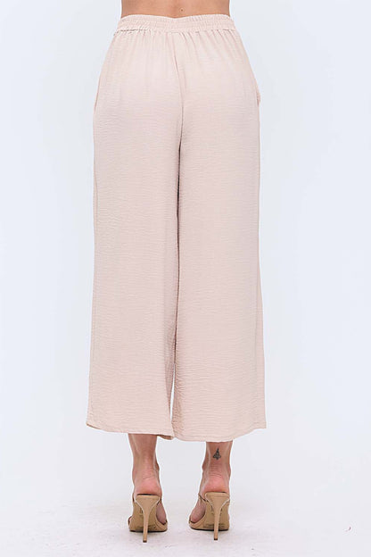 Woman wearing neutral wide leg pants with nude heels on white background