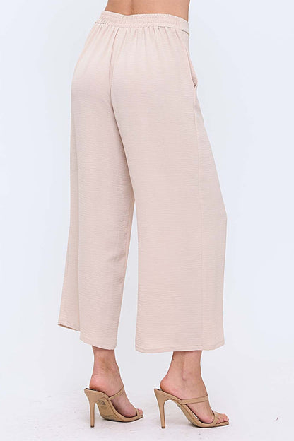 Woman wearing neutral wide leg pants with nude heels on white background