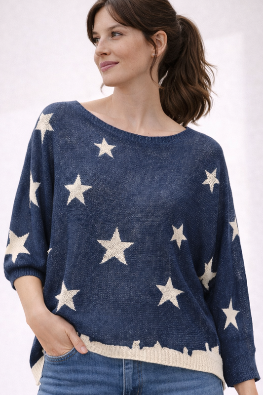 Brunette woman wearing a navy sweater with off-white stars on a white background