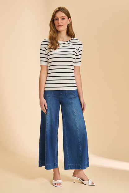 Woman wearing a striped shirt and blue jeans on a beige background