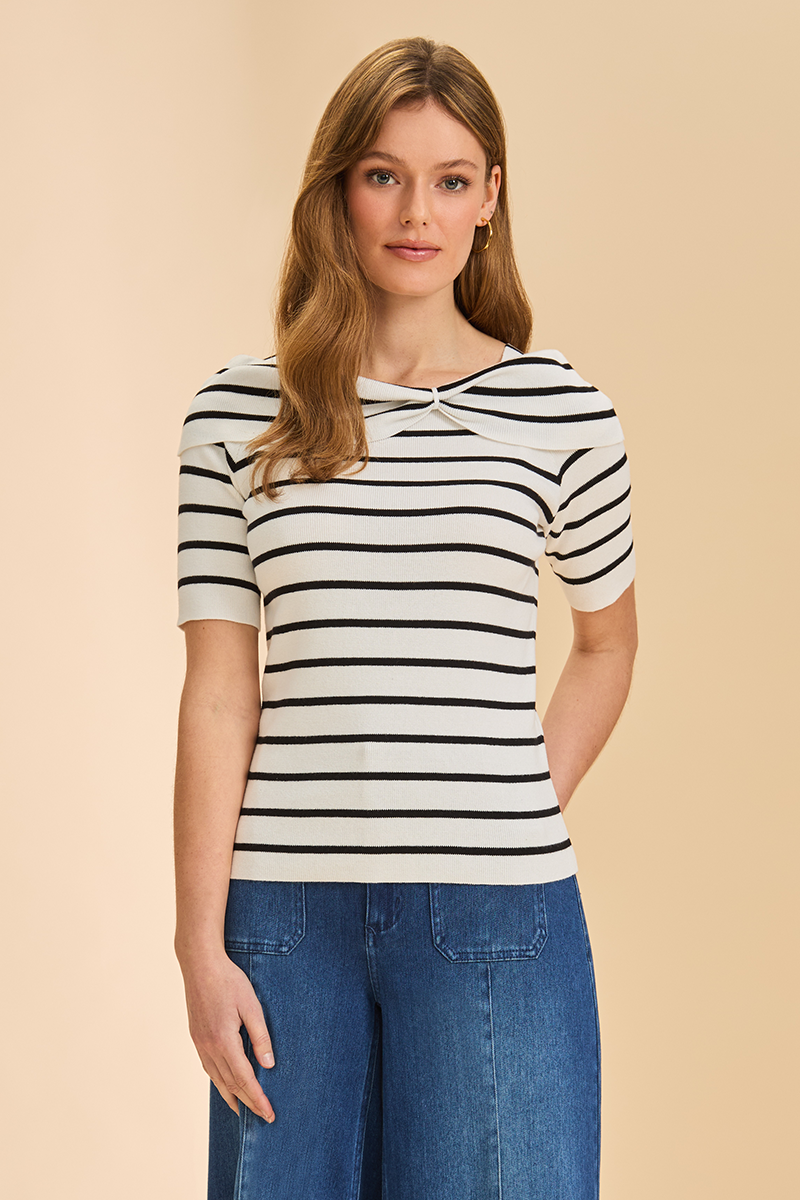 Woman wearing a black and white striped shirt with blue jeans on a beige background
