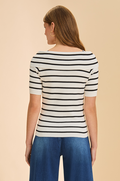Woman wearing a black and white striped shirt with blue pants on a beige background