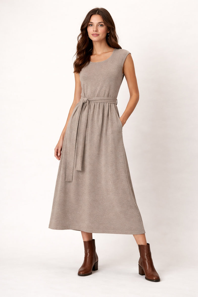Woman wearing a beige dress with a belt on a white background