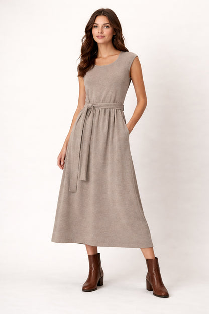 Woman wearing a beige dress with a belt on a white background