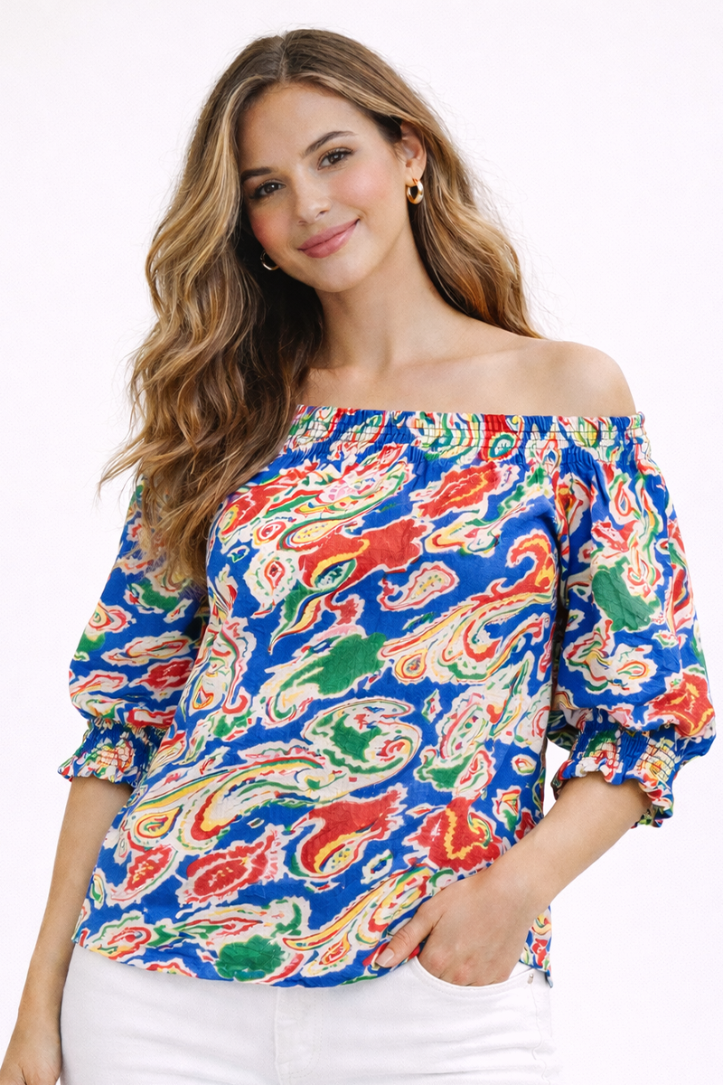 Woman wearing a colorful off-shoulder top with a white background