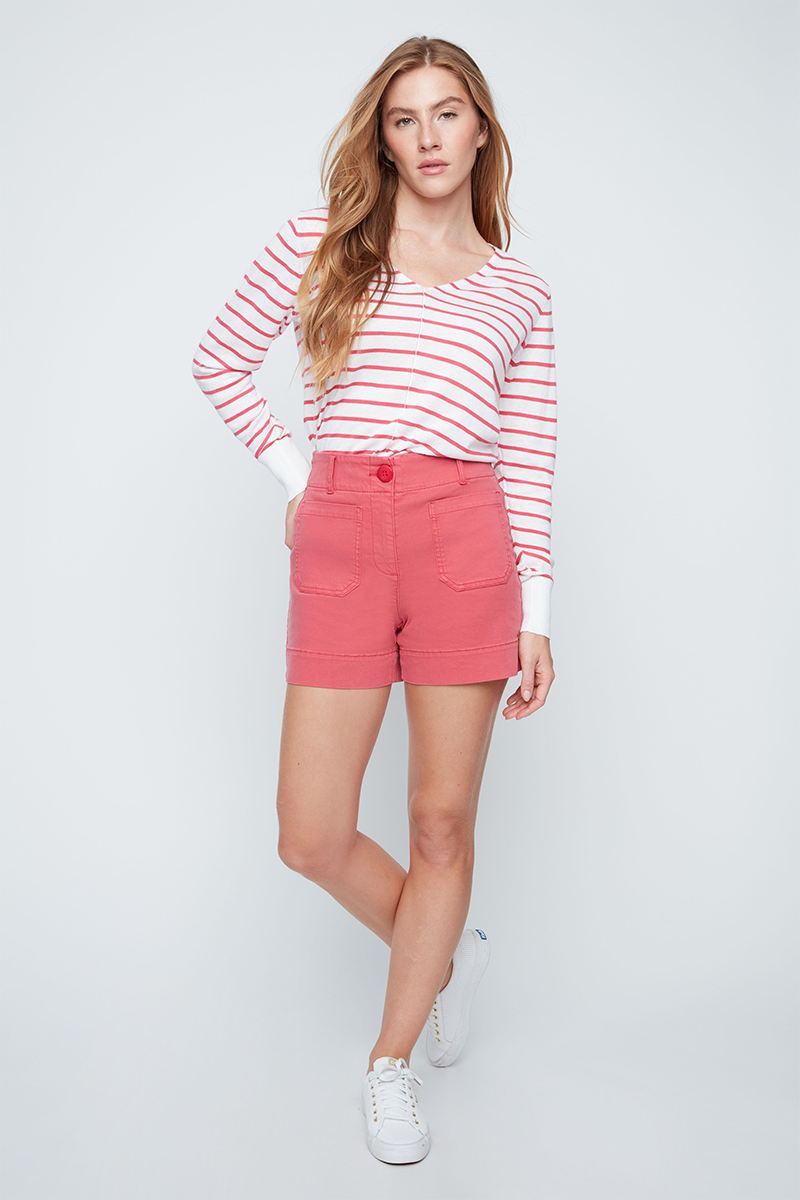 Woman wearing a pink and white striped shirt and pink shorts on a white background