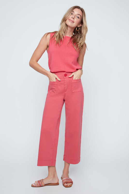 Woman wearing a coral sleeveless top and pants on a white background