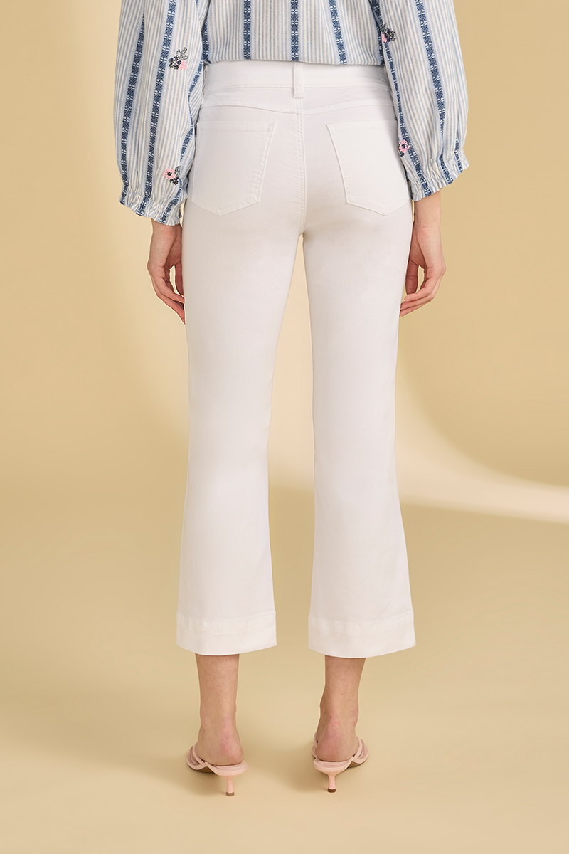 Person wearing white pants with a beige background