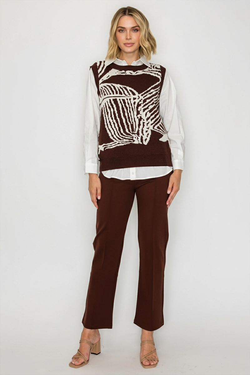 Woman wearing a brown and white patterned top with a white shirt underneath, paired with brown pants on a white background.