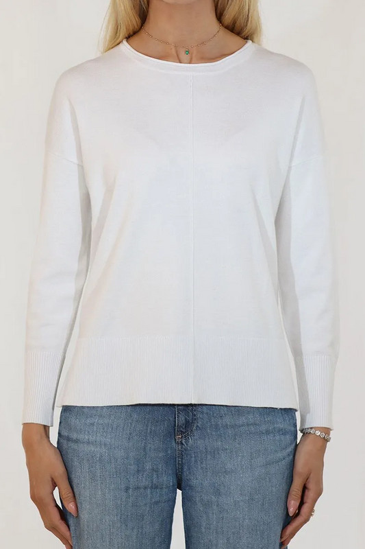 Person wearing a white long-sleeve top and blue jeans against a plain background