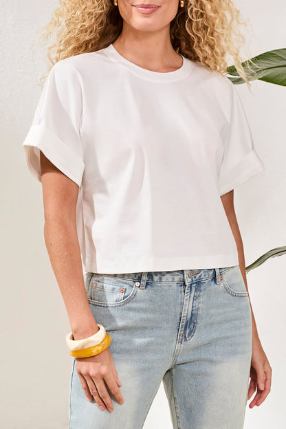 Woman wearing a white oversized t-shirt and light blue jeans against a neutral background