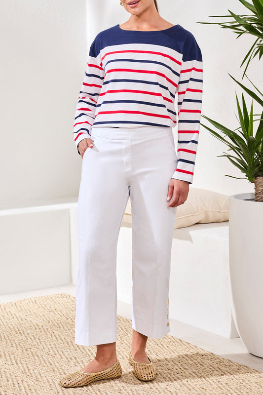 Person wearing a striped sweater and white pants in a home setting
