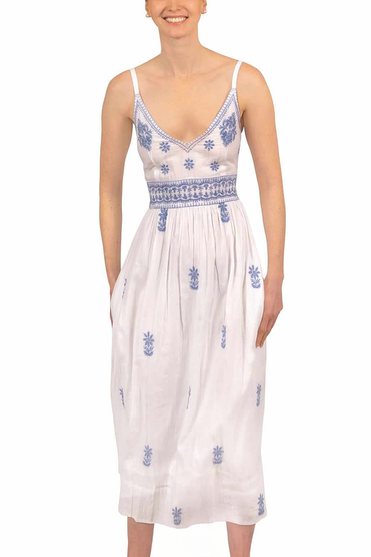Woman wearing a white dress with blue floral embroidery on a white background