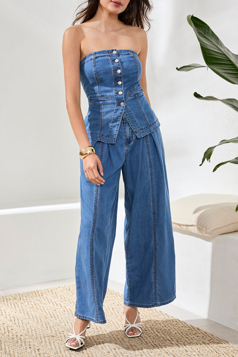 Woman wearing a blue denim strapless top and pants indoors with a plant in the background